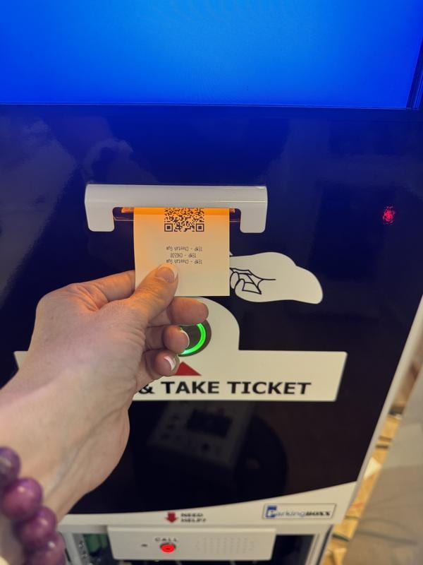 Hand taking a printed thermal ticket from an Entry BOXX parking ticket machine