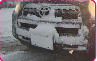 Snow-covered vehicle front plate — actual LPR system photo showing environmental interference