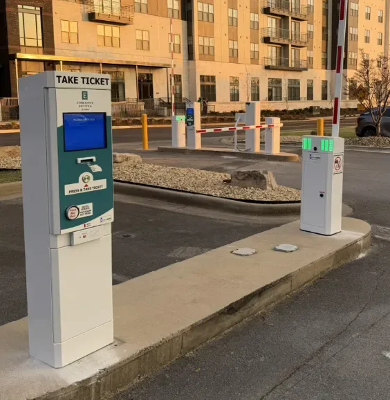 Parking BOXX take-ticket dispenser, barrier gate and exit pedestal installed at a hotel lot at dusk